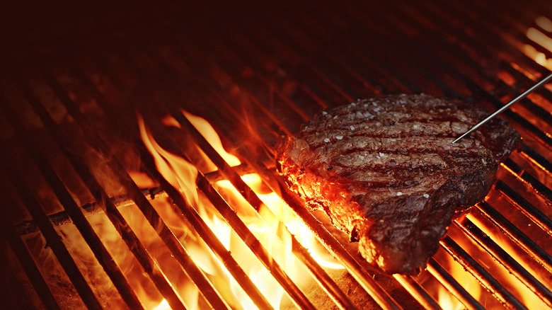 Cooking a ribeye steak over an open flame grill