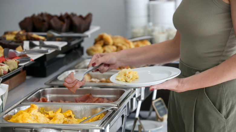 Person selecting food at buffet restaurant