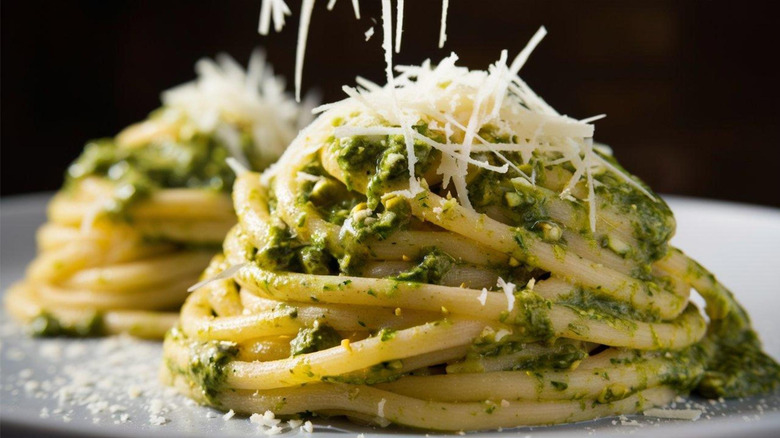 Spaghetti noodles coated with fresh pesto and topped with shredded parmesan