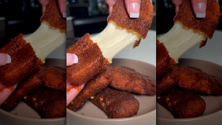 Hand pulls apart homemade mozzarella sticks
