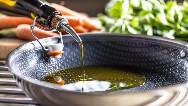 Olive oil being poured into a modern non-stick pan