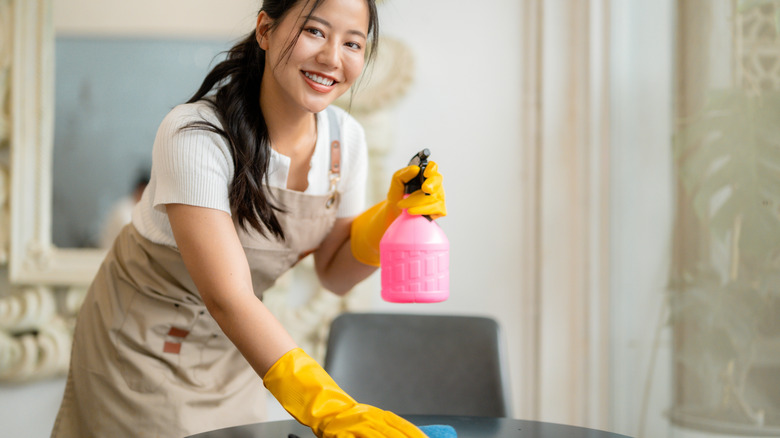 A smiling female server wipes down a table