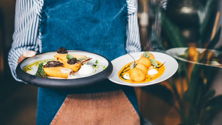 A server bringing plates of food to a table in a restaurant