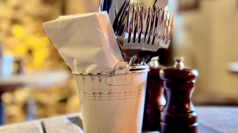 A cutlery pot, with knives, forks, and napkins