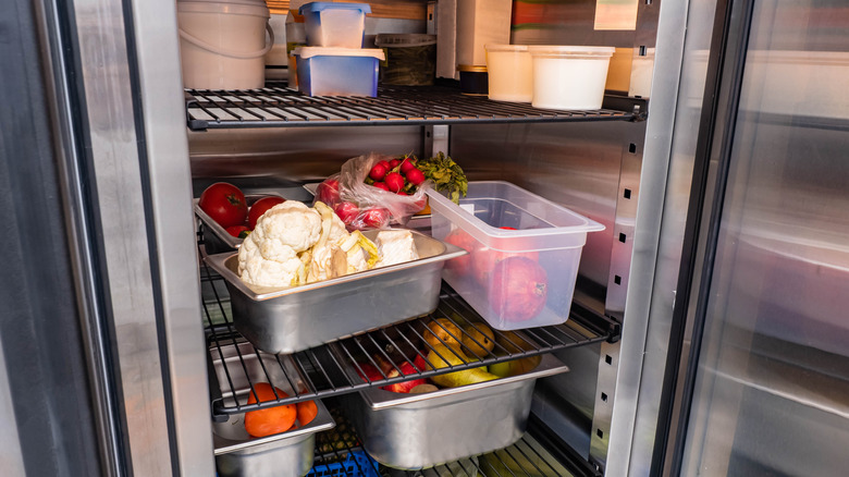 An open restaurant refrigerator with fresh produce inside