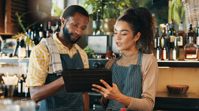 Two restaurant servers discussing something they're looking at on an iPad