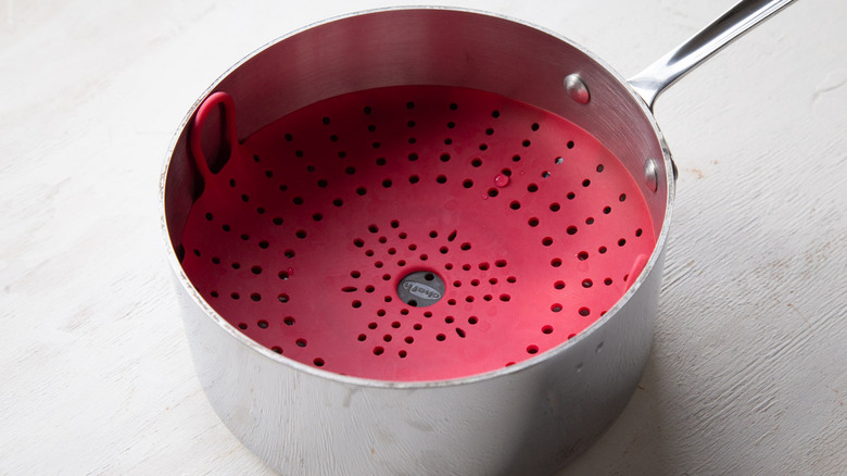 metal pot with a red plastic basket inside