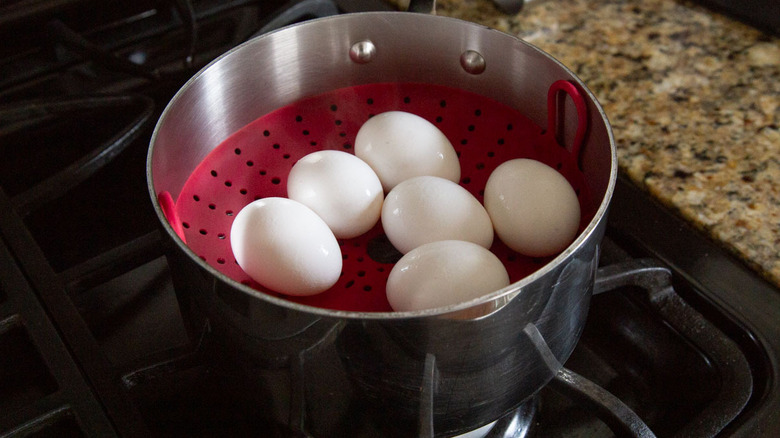 eggs in a metal pot with a red plastic basket inside
