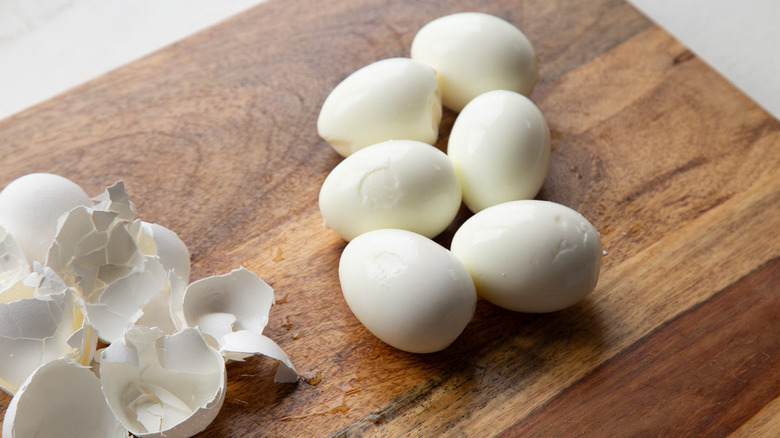 peeled eggs and shells on a piece of wood