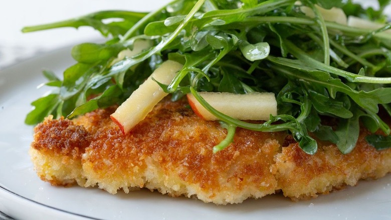 Breaded chicken cutlet topped with apple arugula salad
