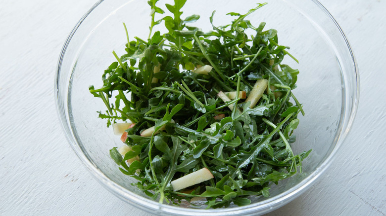 arugula and chopped apples in a clear bowl