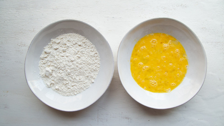 flour and beaten eggs in white bowls