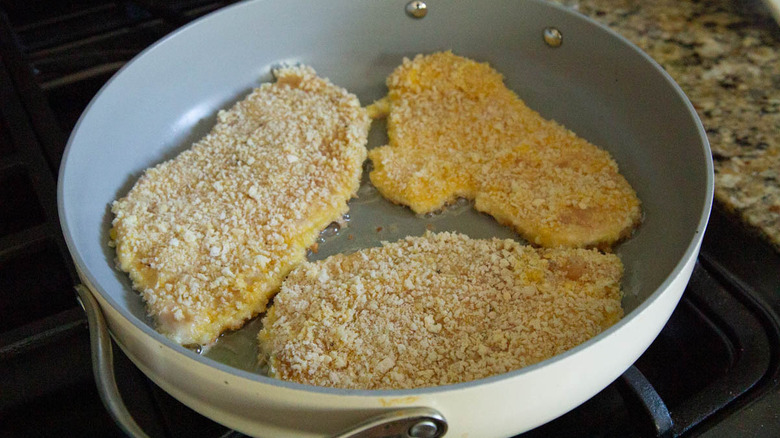 breaded chicken cutlets in a frying pan