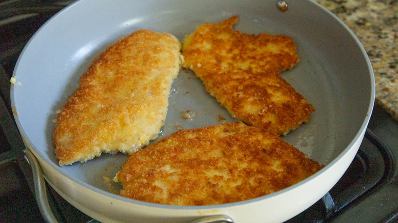 browned breaded chicken cutlets in a frying pan