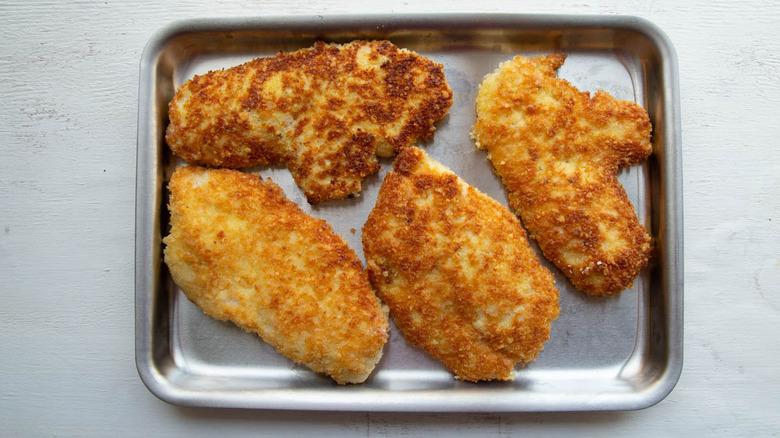 browned breaded chicken cutlets in a baking pan