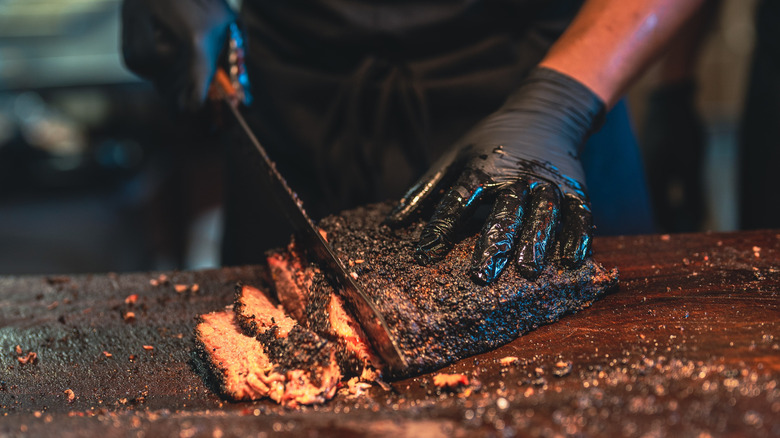 Chef prepping barbecue brisket on cutting board