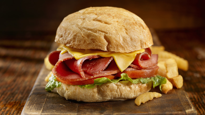 Fried bologna sandwich on a wood board with fries