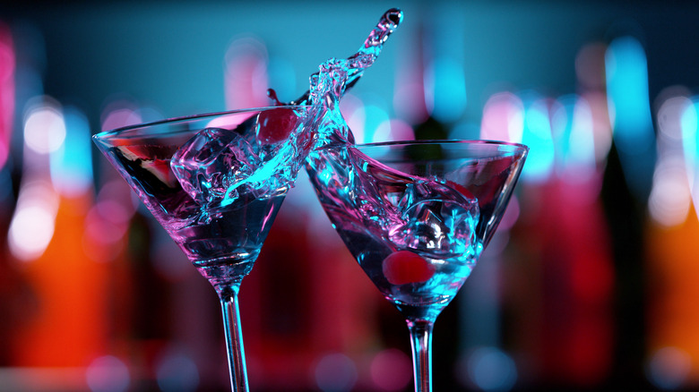 Two martini glasses clinking together and spilling liquid