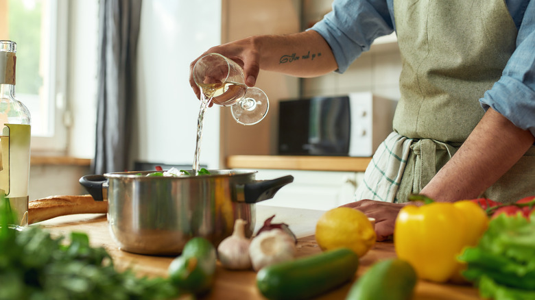 home cook adding wine to a pot