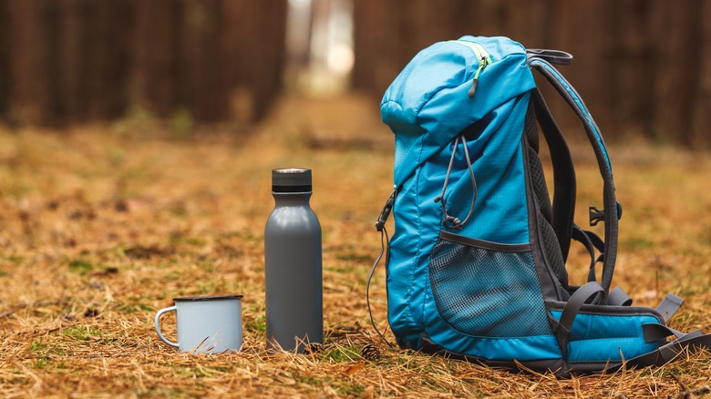backpack thermos and cup on ground