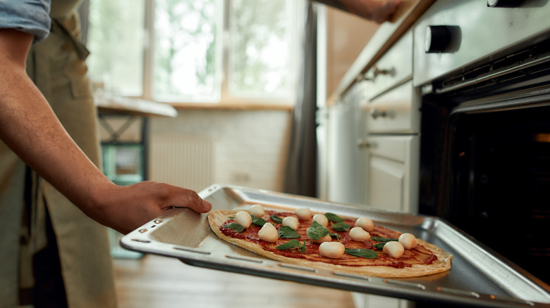 Man cooking pizza in oven