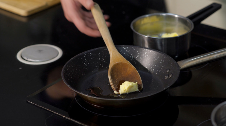 A person frying butter in a pan