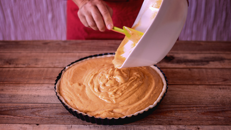 Pouring pumpkin pie filling into crust
