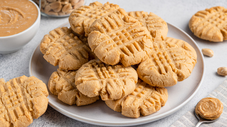 Plate of peanut butter cookies with spoon and bowl of peanut butter