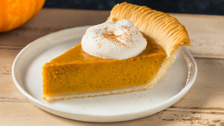 Slice of pumpkin pie and whipped cream on a plate