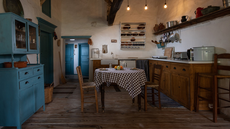 A vintage country kitchen with one blue cabinet, and full storage shelves and racks