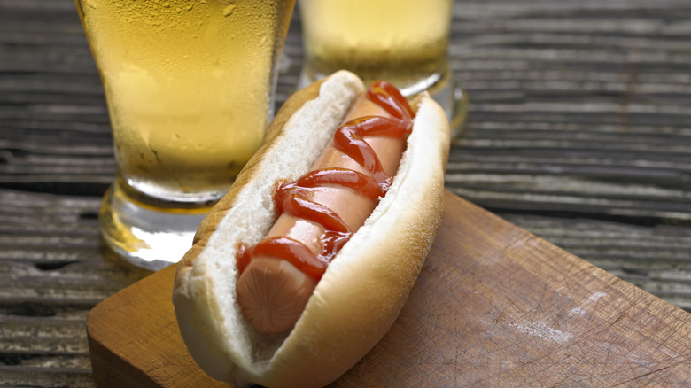 Hot dog with ketchup and glasses of beer