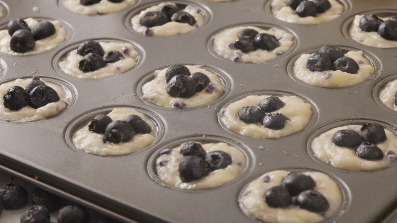 Muffin tray with batter and blueberries close up