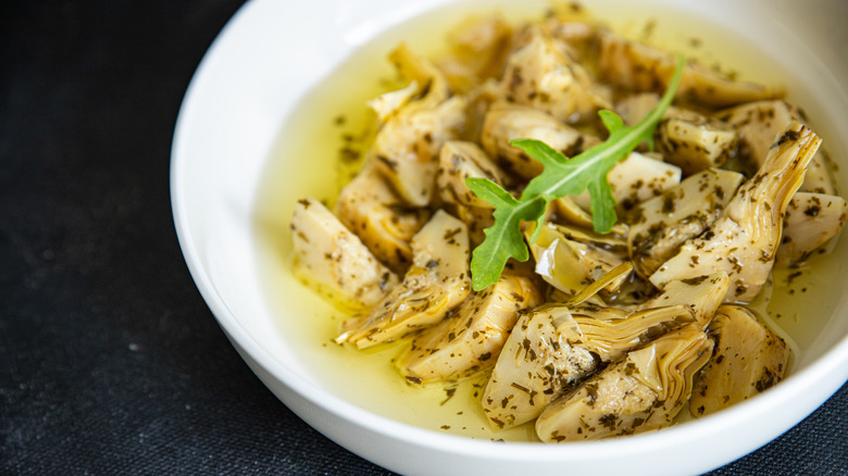 Marinated artichokes in a bowl with arugula leaf