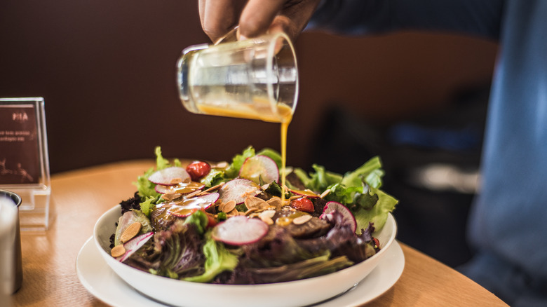 pouring dressing over salad