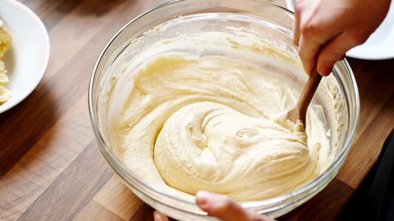 A person stirs a bowl of cake batter