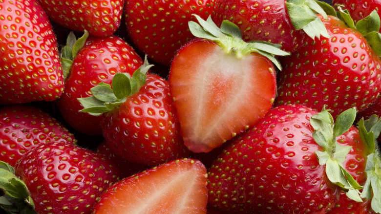 Sliced strawberry on pile of whole strawberries