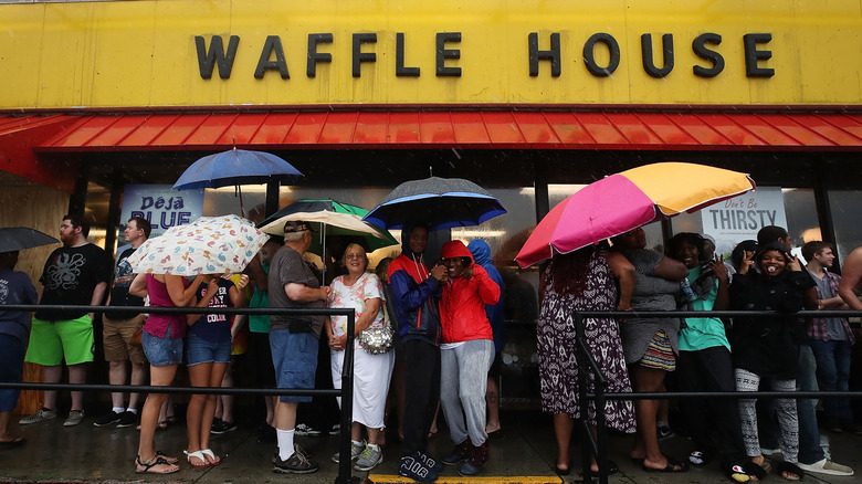 People holding umbrellas, waiting to get into a Waffle House