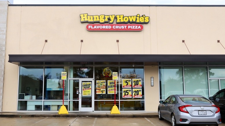 A Hungry Howie's storefront with yellow and red signs advertising its signature flavored crust pizza and curbside pickup