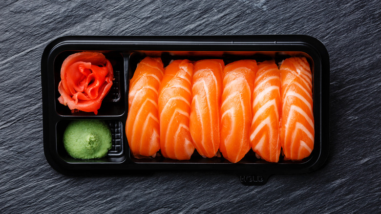 salmon nigiri sushi with wasabi and pickled ginger in a supermarket container