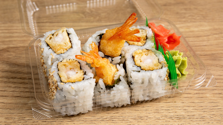 A plastic takeout container of pre-made tempura shrimp sushi rolls