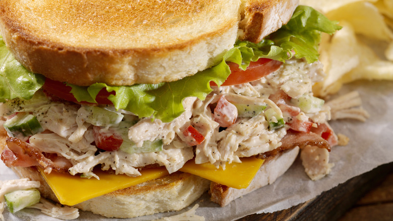 A scooper scoops chicken salad out of a metal tray