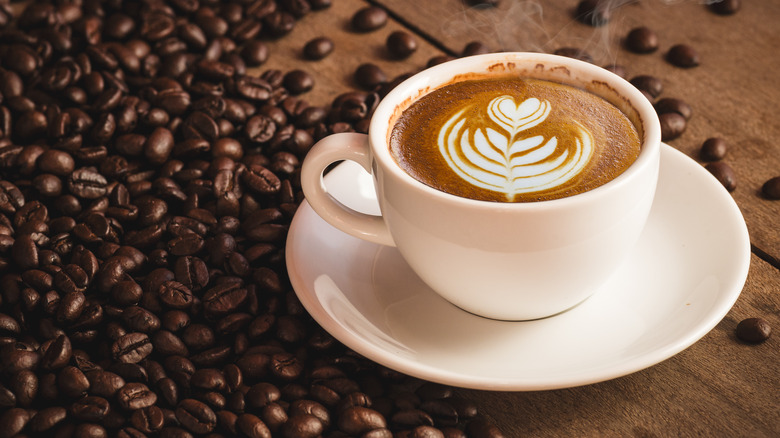 saucer with coffee and coffee beans beside it