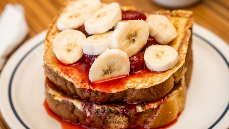 Challah french toast on  white plate with strawberry compote on top