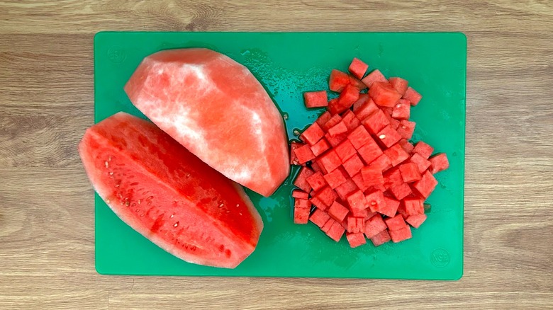 Watermelon cubed and quartered on green cutting board