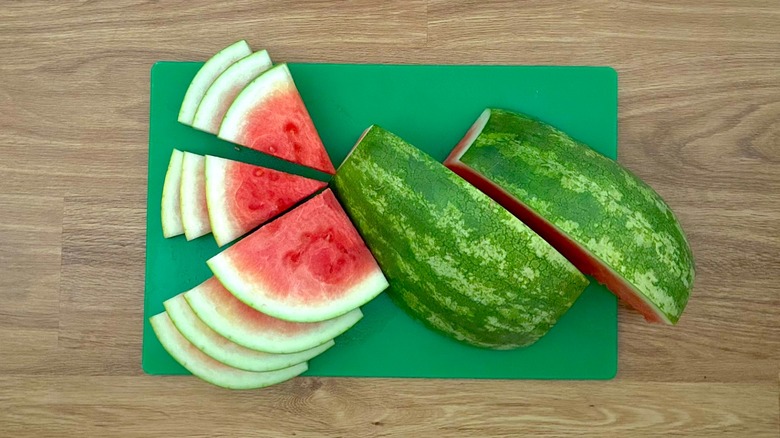 Watermelon cut into wedges and quartered on green cutting board