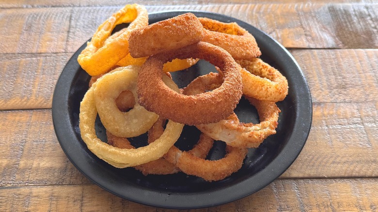 Black plate of fried onion rings