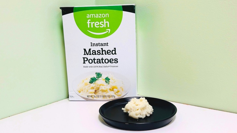 Plate of mashed potatoes in front of a box of Amazon Fresh instant mashed potatoes