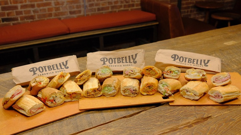 A lineup of 10 subs from Potbelly on a wooden table