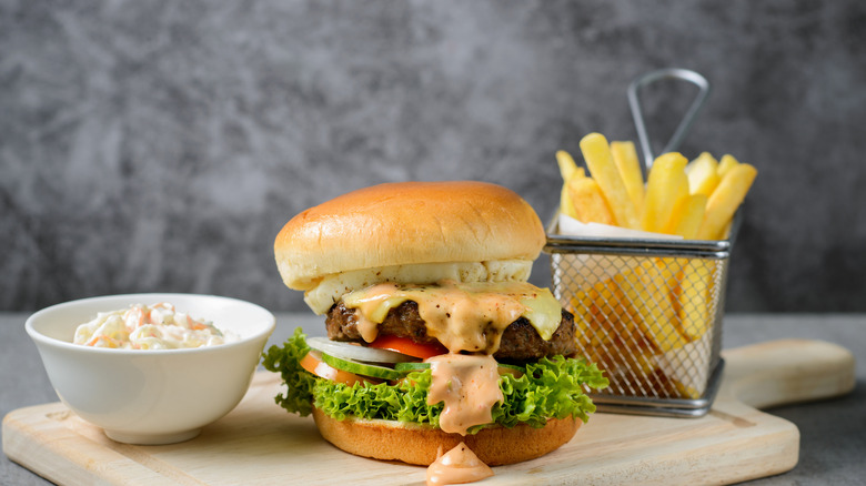 A cheeseburger with fries and coleslaw from a fast food restaurant