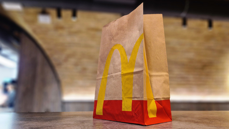 a McDonald's bag sitting outside against a dark background and a bridge